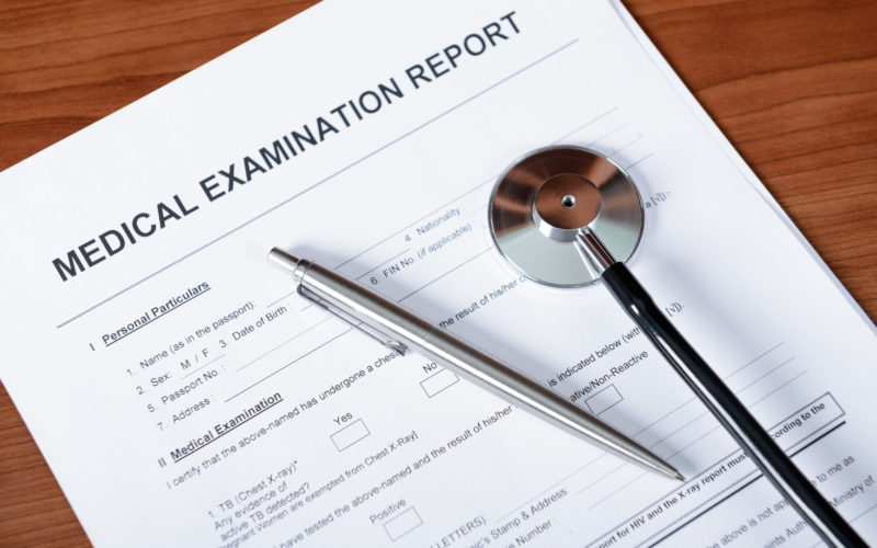 Medical report blank form with pen and stethoscope on table.